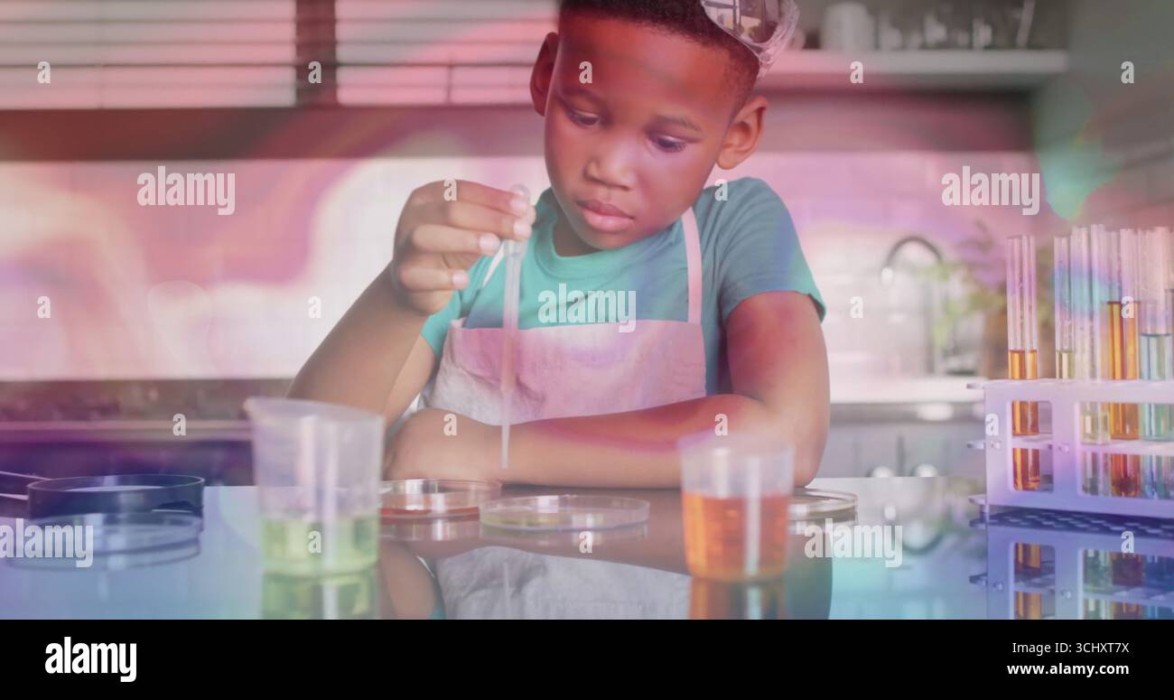 Garçon portant tablier conduisant l'expérience dans la cuisine, avec compte-gouttes, boîtes de Petri et tubes à essai Banque D'Images