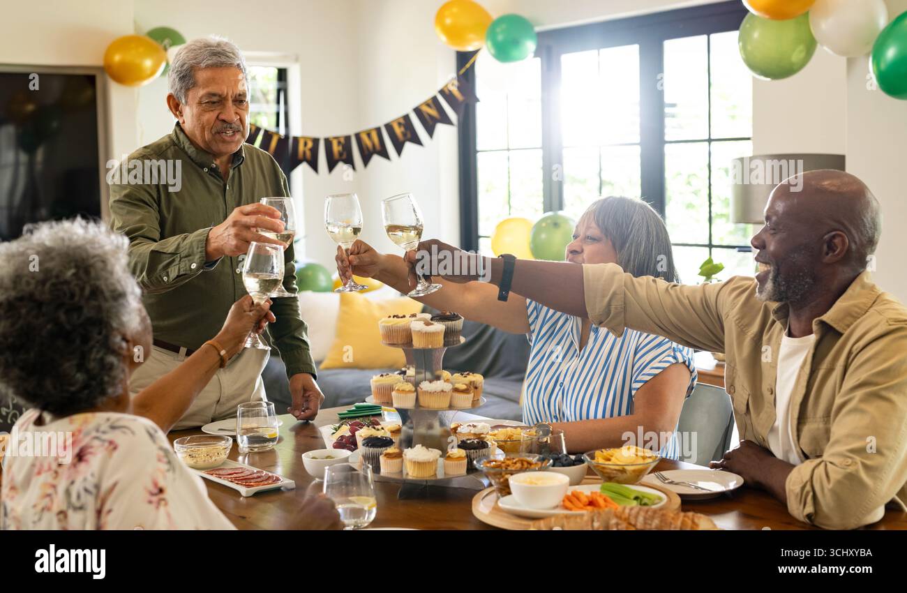 Groupe d'amis seniors grillant avec des verres à vin à la maison pendant la fête Banque D'Images
