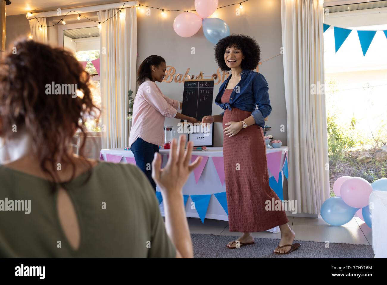 Douche de bébé, amies féminines diverses riant et appréciant la fête de révélation de genre, à la maison Banque D'Images
