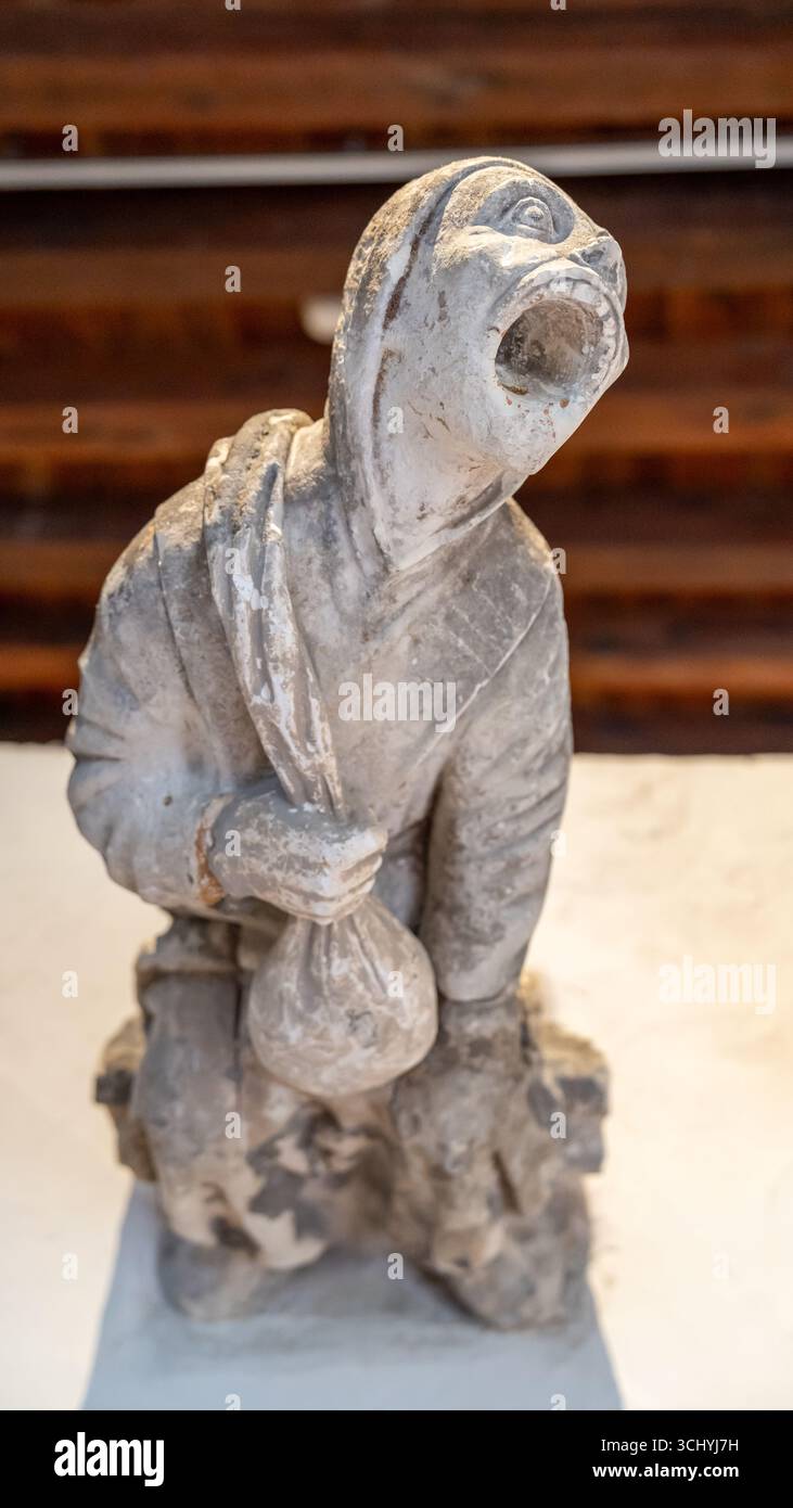 Gros plan sur une ancienne statue en pierre représentant un mendiant tenant un sac et criant Banque D'Images