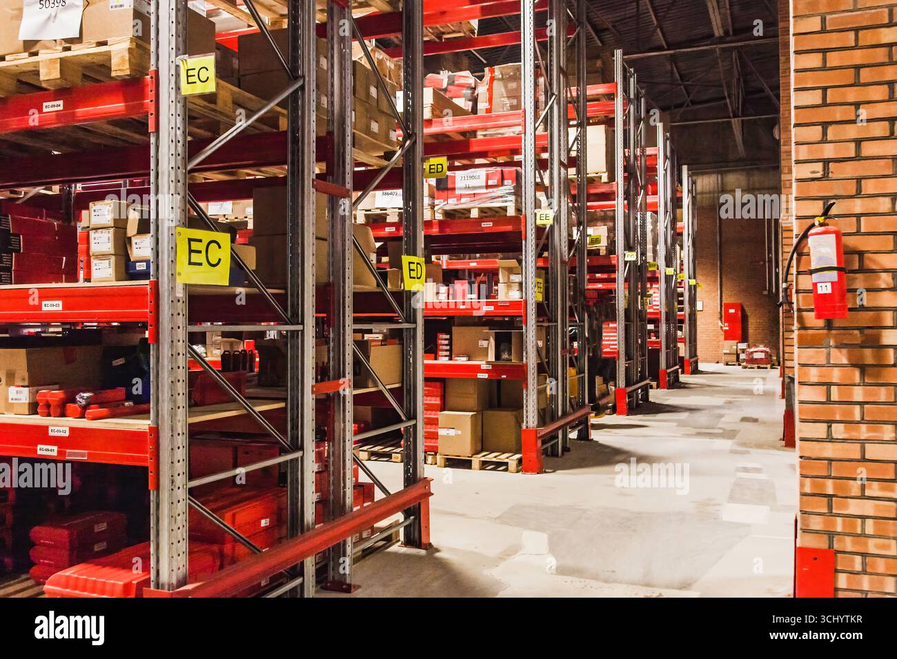 Entrepôt lumineux montrant plusieurs étagères stockées avec diverses marchandises arrangées soigneusement. Les boîtes sont étiquetées et organisées pour faciliter l'accès. Banque D'Images