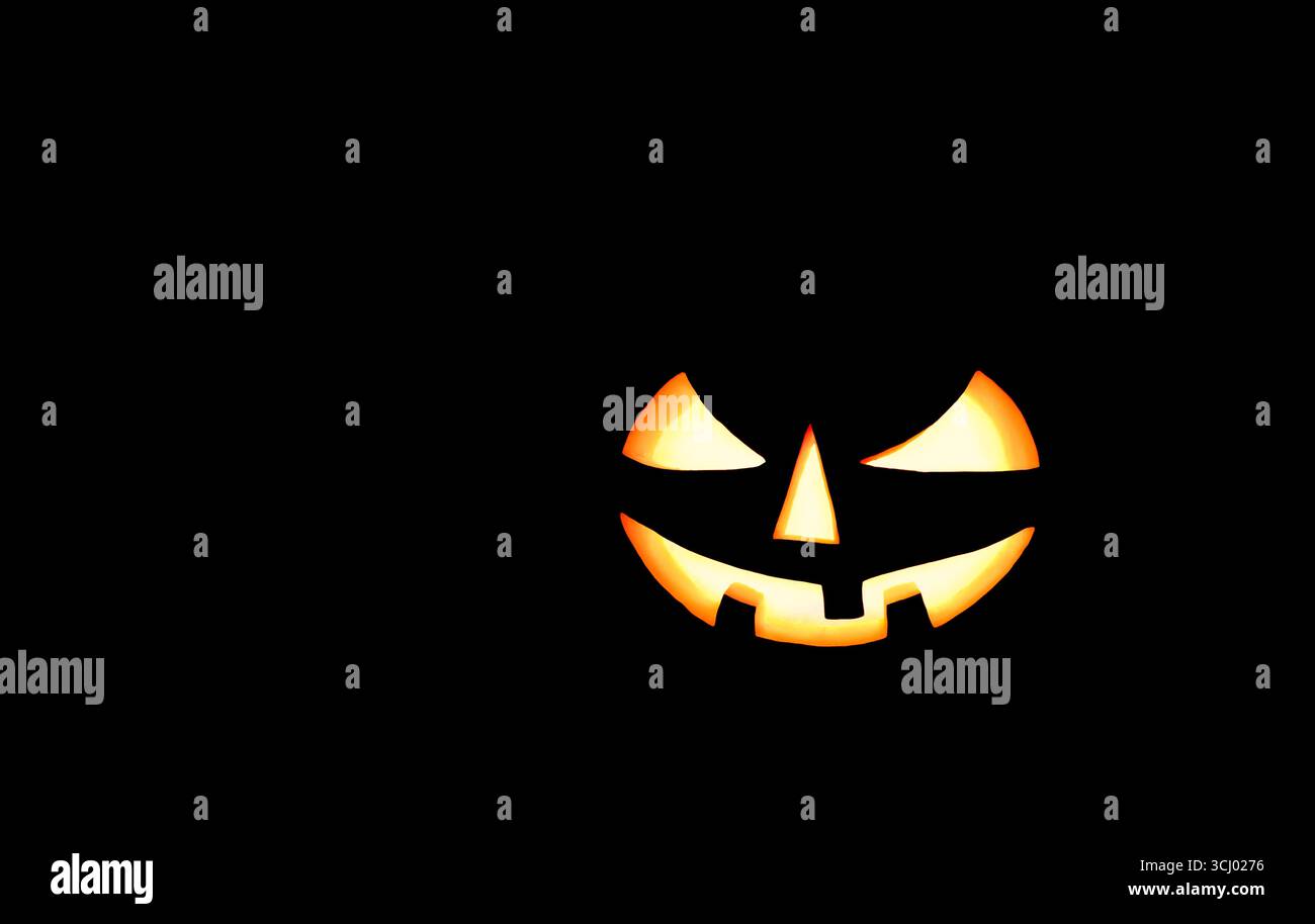 Citrouille d'Halloween avec les yeux brillants sur fond noir. Spooky Halloween citrouille, Jack O Lantern, avec un visage maléfique sur fond noir. Banque D'Images