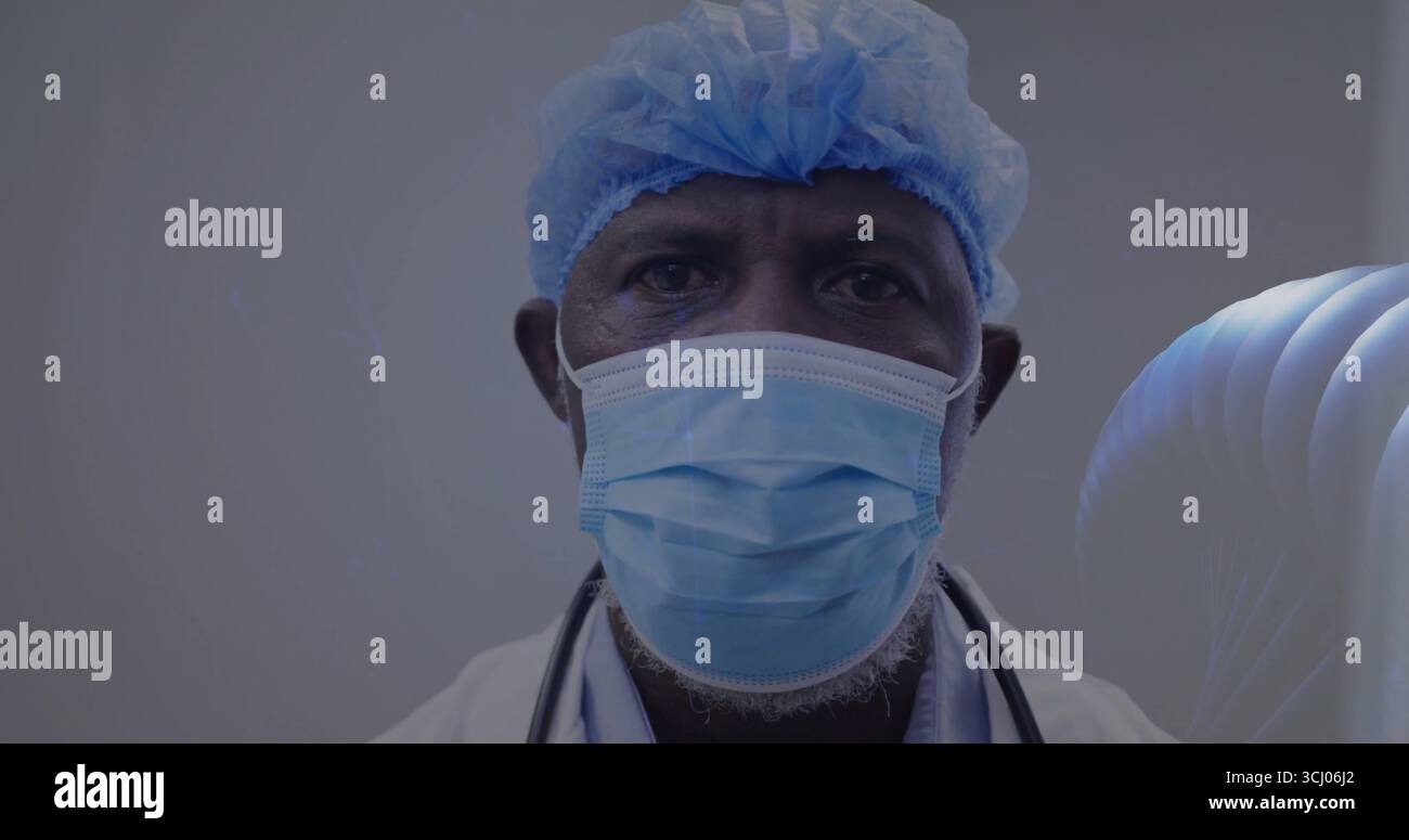 Posant médecin masculin senior portant une casquette chirurgicale et un masque et une blouse de laboratoire en clinique, avec stéthoscope Banque D'Images