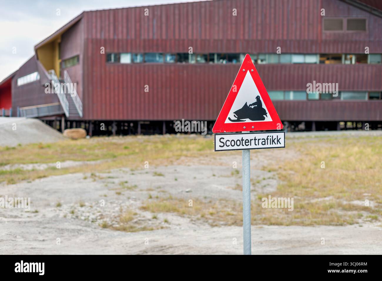 Panneau de signalisation pour motoneige Longyearbyen Svalbard Norvège // LONGYEARBYEN, Svalbard — Un panneau de signalisation indique la circulation de scooters à Longyearbyen, le plus grand village et centre administratif du Svalbard, un archipel norvégien situé entre l'océan Arctique et la mer du Groenland. Le panneau comporte un symbole d'avertissement triangulaire rouge avec la silhouette noire d'une motoneige, accompagné d'une plaque rectangulaire ci-dessous qui indique « Scootertrafikk », qui est norvégien pour le trafic de motoneige. Longyearbyen est un établissement unique, connu pour son environnement arctique extrême et son rôle de porte d'entrée pour les touris Banque D'Images