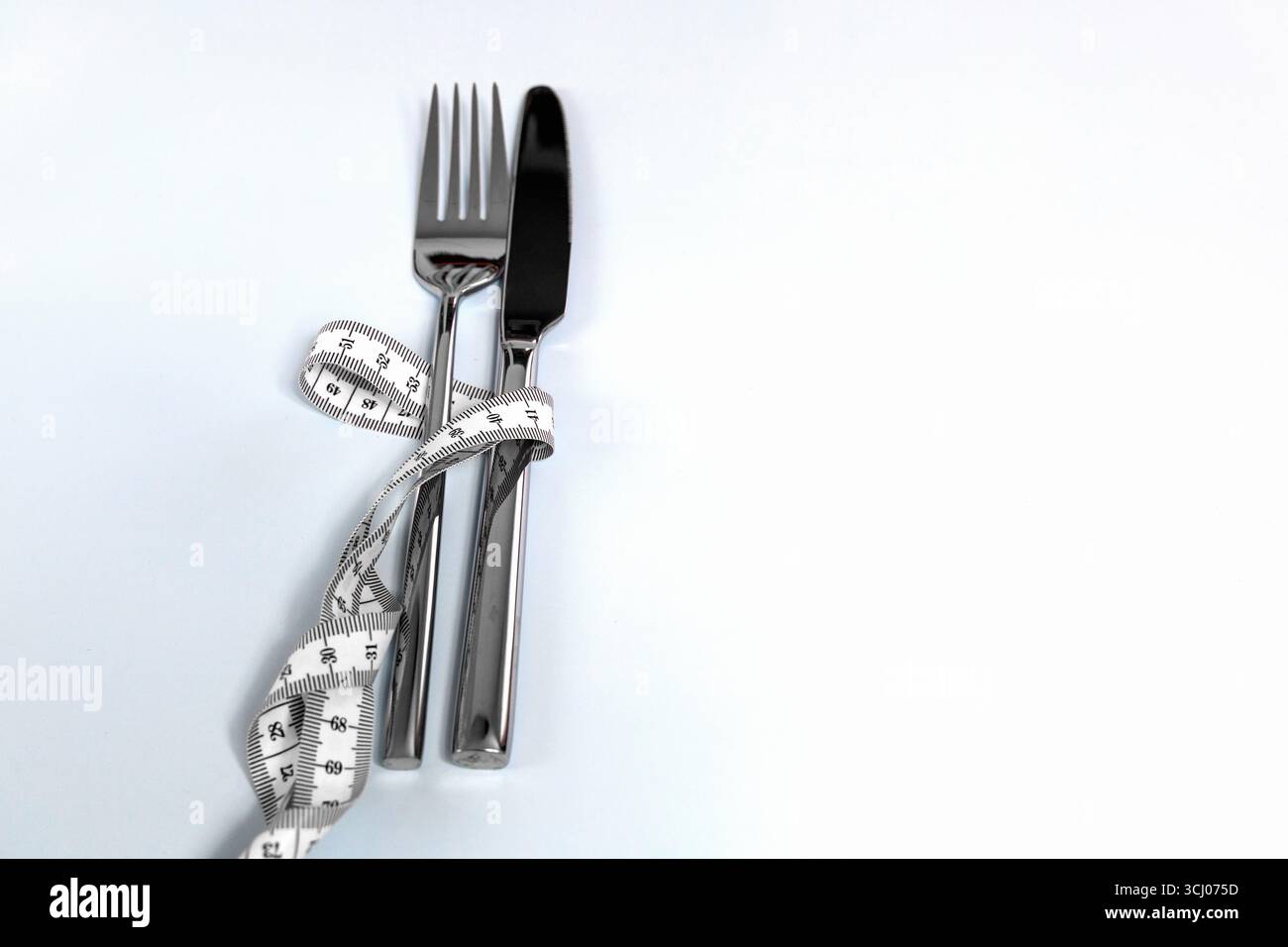 Fourchette et couteau enveloppés dans un ruban à mesurer. Photo de haute qualité Banque D'Images
