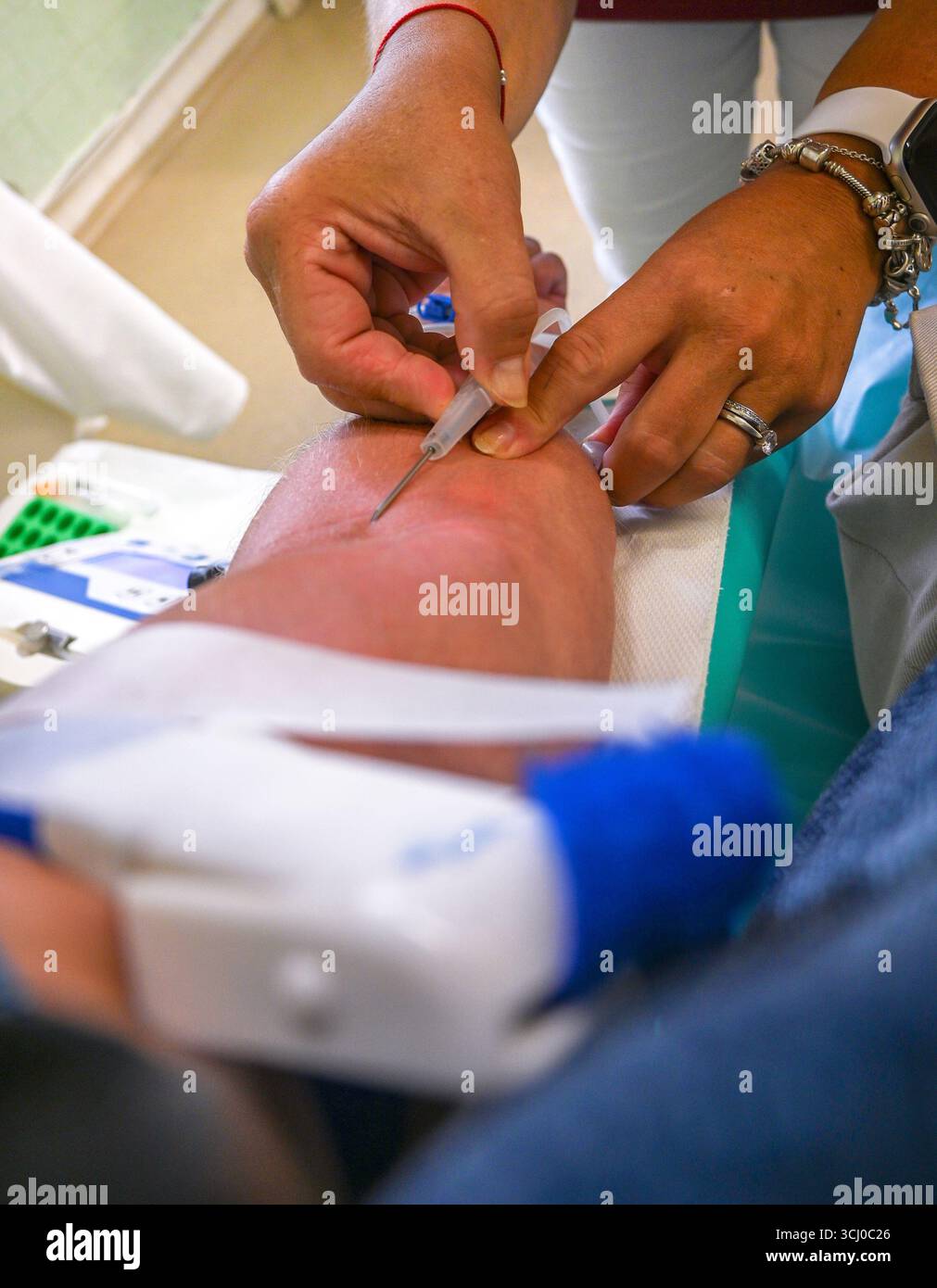 Professionnel de santé réalisant une ponction veineuse, prélevant un échantillon de sang dans la veine du patient. Banque D'Images