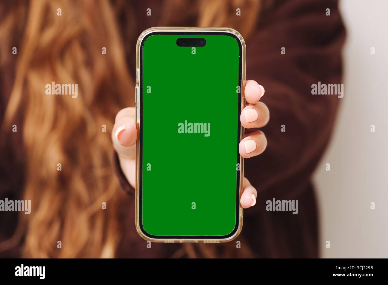 Smartphone avec écran vert. Ecran mobile vierge tenu à la main. Gadget technologique pour la conception de maquette. Contexte de communication numérique. Banque D'Images