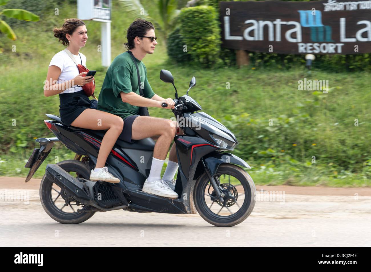 KOH LANTA, THAÏLANDE, DEC 01 2024, une paire de touristes conduisent une moto louée le long d'une route de campagne Banque D'Images