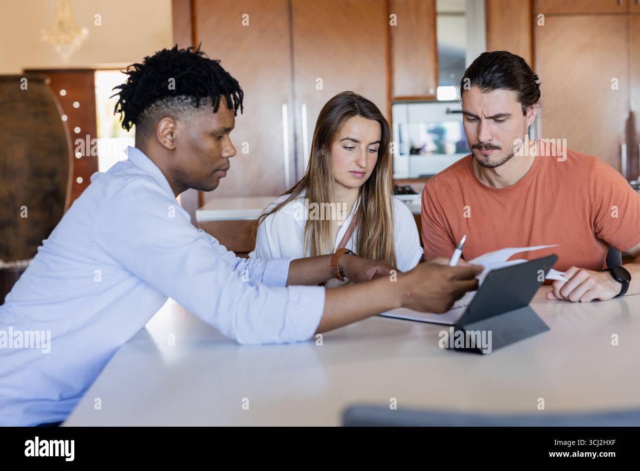 Divers amis collaborant sur un projet avec une tablette et des documents à la maison. Collaboration, travail d'équipe, technologie, brainstorming, créativité, réunion Banque D'Images