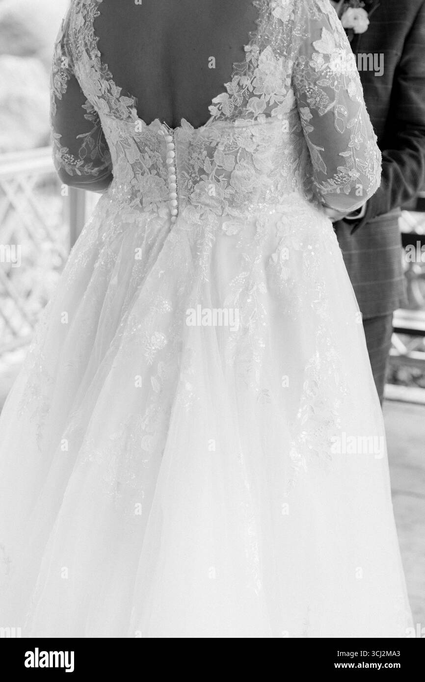 Mariée présente de superbes détails de dentelle sur sa robe comme elle échange des vœux dans un cadre magnifique en plein air. Banque D'Images