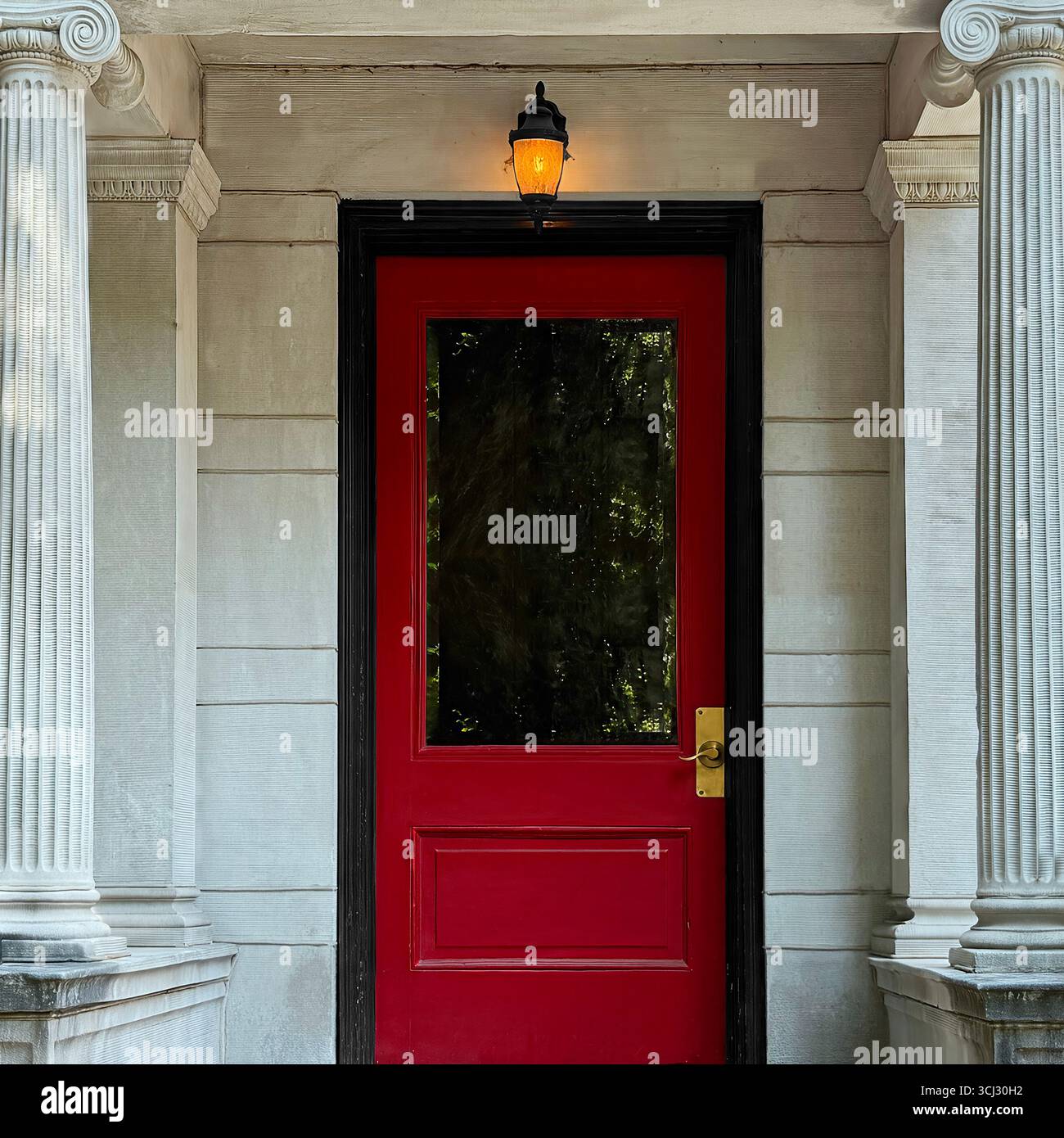 Porte rouge et lanterne au-dessus, encadrées par de hautes colonnes de pierre sur une façade historique de maison de ville de Chicago. Banque D'Images