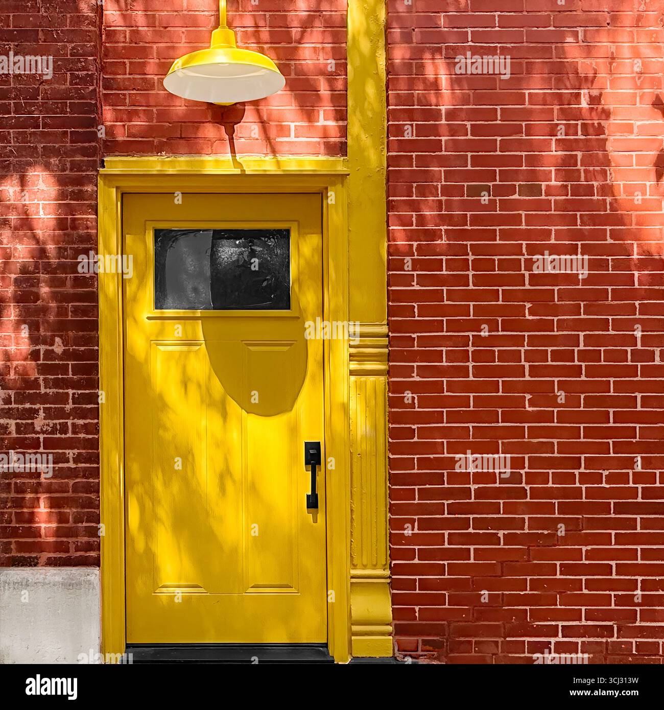 Porte d'entrepôt peinte en jaune industriel avec lampe suspendue en métal sur le mur de Chicago en briques rouges. Banque D'Images