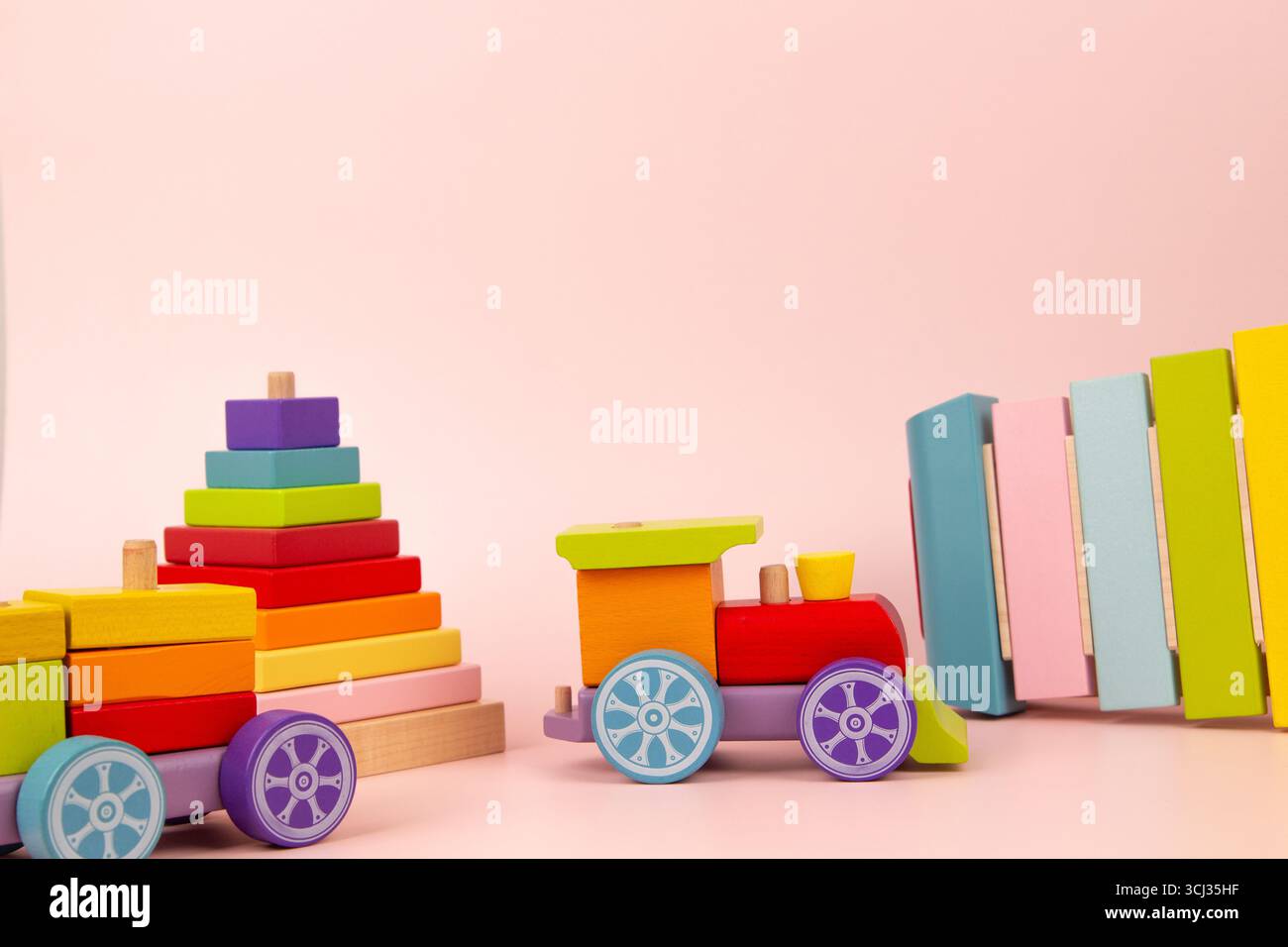 Fond de jouets pour bébés. Jouets éducatifs et musicaux en bois naturel sur fond rose pastel. Vue de face Banque D'Images