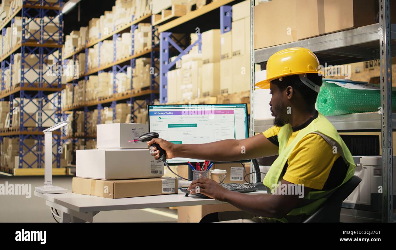 Membre du personnel noir utilisant un lecteur de codes-barres pour traiter les étiquettes d'expédition sur les boîtes des racks de stockage industriels. Lecture des étiquettes awb pour un service de suivi des colis et une logistique précise. Caméra A. Banque D'Images