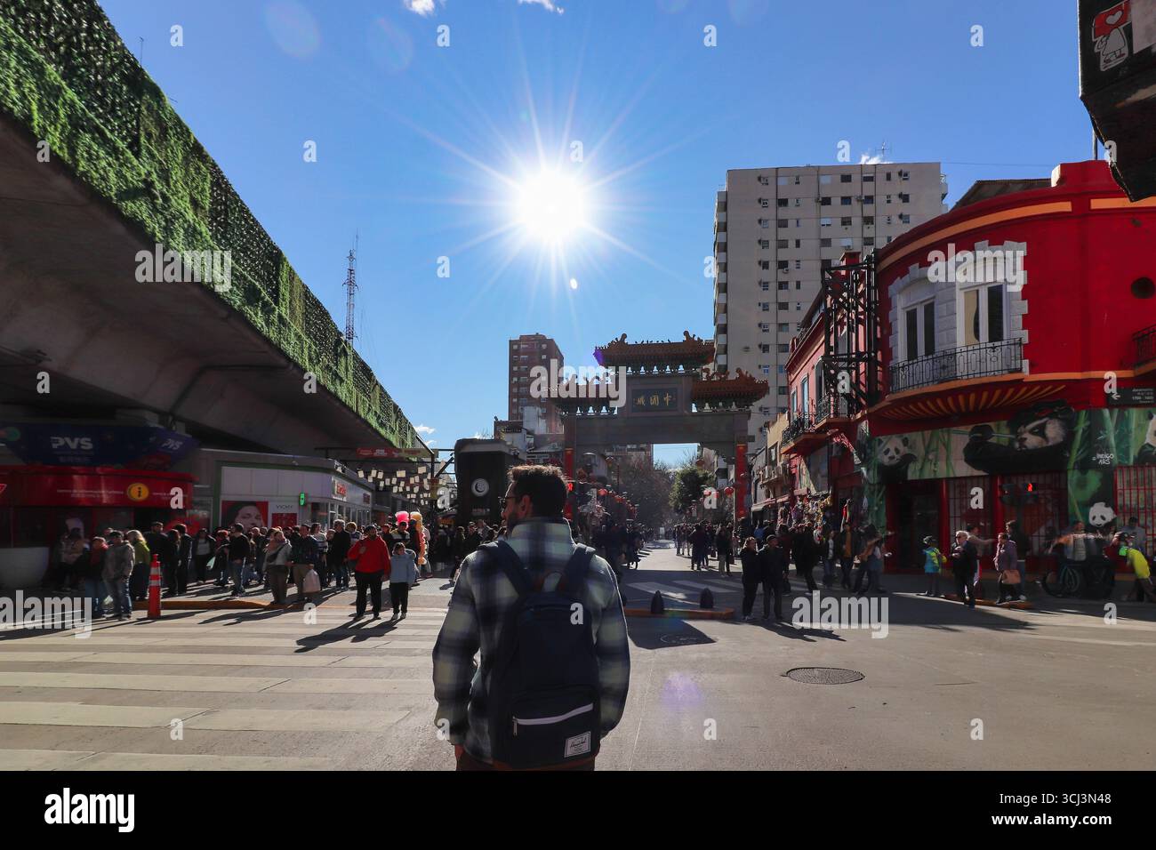 Un visiteur observe l'arc d'entrée emblématique du quartier chinois de Belgrano, en Argentine, sous un soleil radieux qui illumine l'activité urbaine vibrante. Banque D'Images