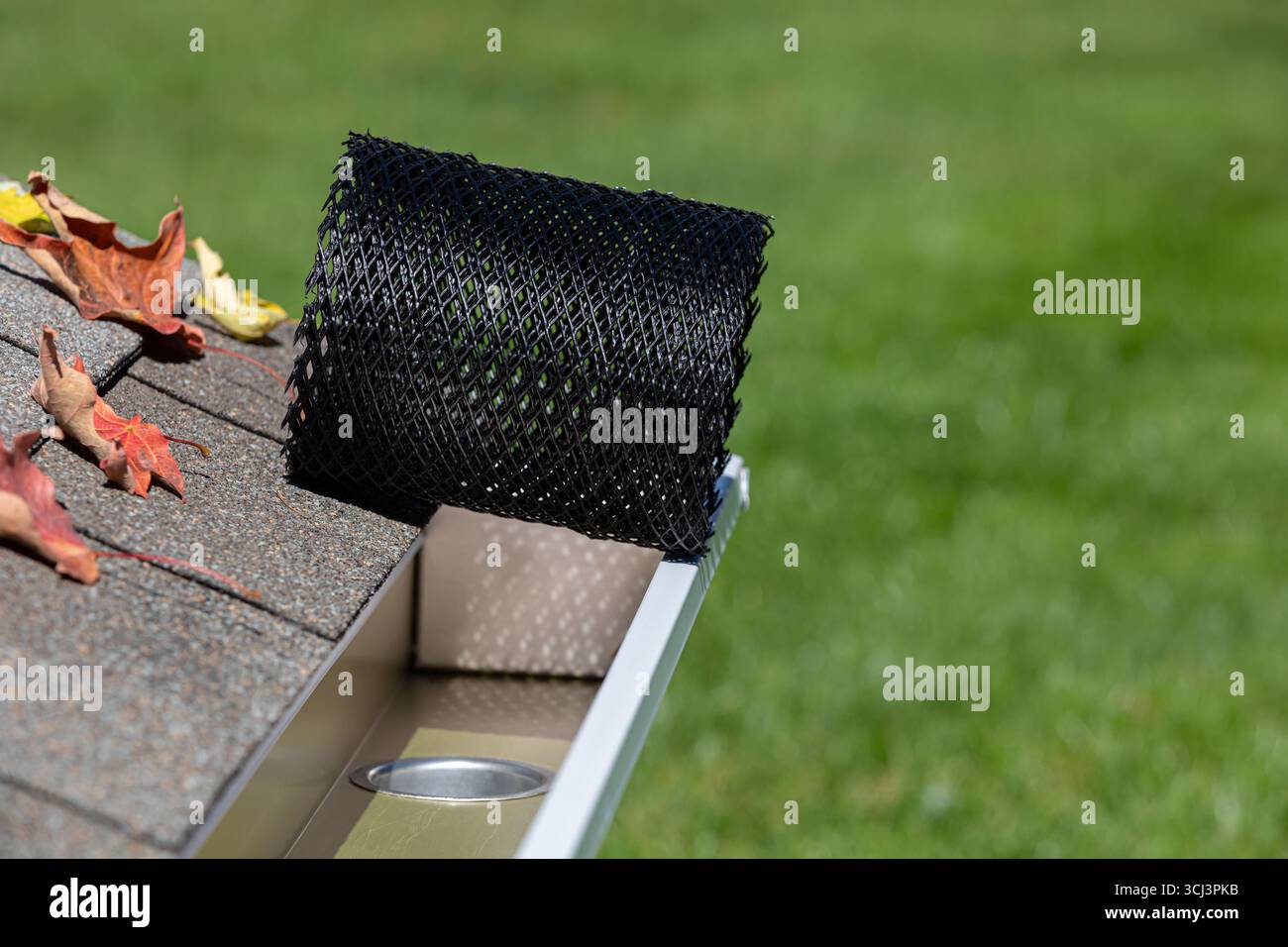 Installation d'un tamis à mailles de protection de gouttière sur une gouttière de pluie. Entretien de la maison, travaux de triage et concept de dommages au toit Banque D'Images
