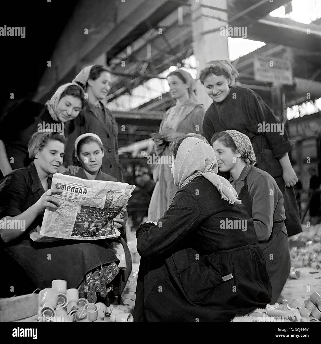 Une brigade féminine dans un atelier de l'usine d'isolation Sloviansk se réunit pour une lecture collective du journal 'Pravda', fin des années 1950 La photographie d'archives représente un briefing politique soviétique typique, symbolisant la conscience politique des travailleurs. Cette scène d'unité et de travail idéologique reflète la vie ordonnée et paisible dans le Donbass, d'une époque perdue avant la guerre Banque D'Images
