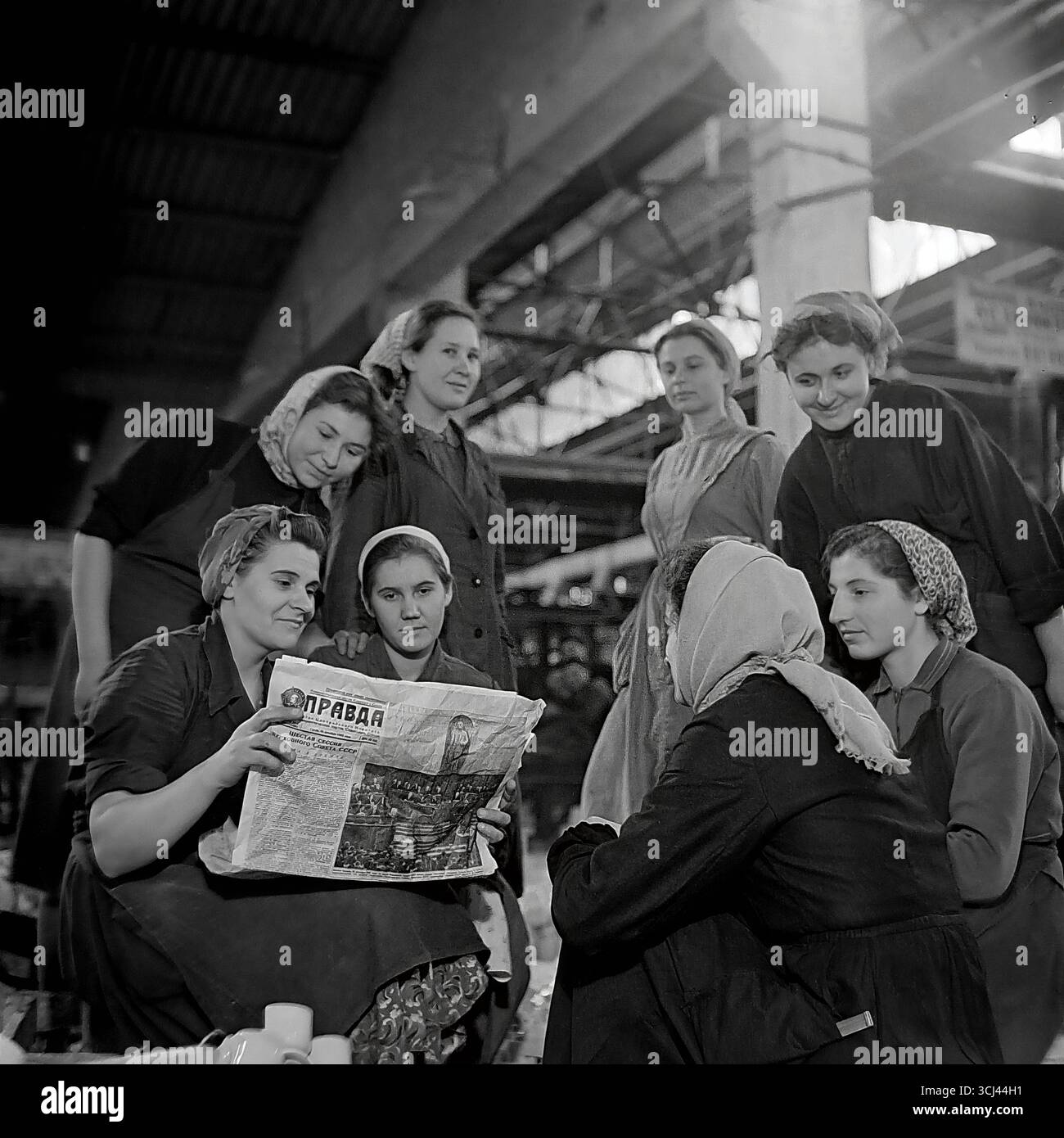 Une brigade féminine dans un atelier de l'usine d'isolation Sloviansk se réunit pour une lecture collective du journal 'Pravda', fin des années 1950 La photographie d'archives représente un briefing politique soviétique typique, symbolisant la conscience politique des travailleurs. Cette scène d'unité et de travail idéologique reflète la vie ordonnée et paisible dans le Donbass, d'une époque perdue avant la guerre Banque D'Images