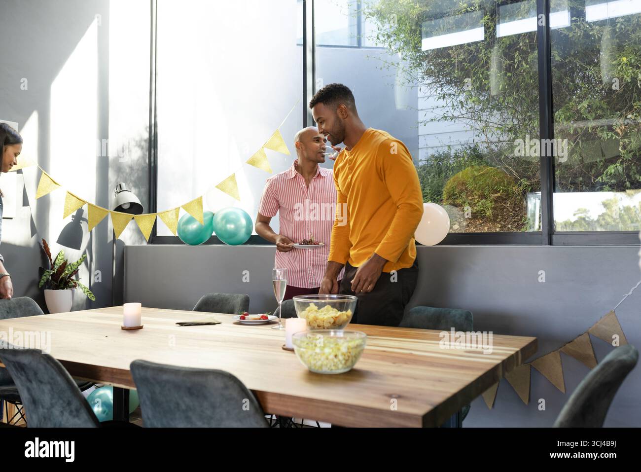 Amis se réunissant à la maison, dégustant des collations et des boissons pendant la célébration festive Banque D'Images