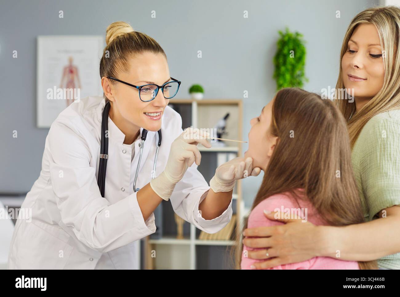 Le médecin prend un écouvillon de gorge de l'enfant patient que la mère réconforte dans la clinique Banque D'Images