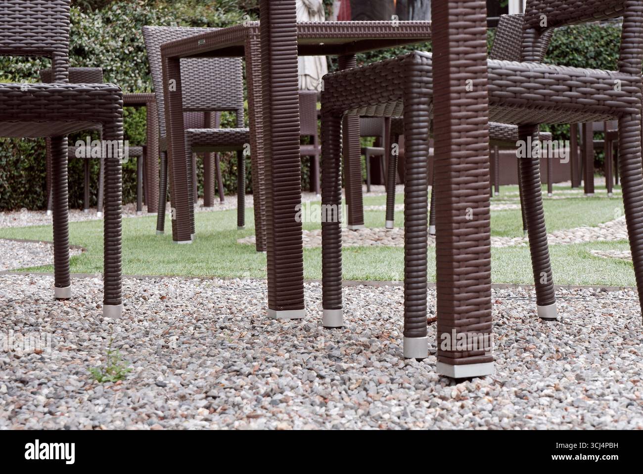 chaises en rotin artificiel brun en osier et table dans le jardin avec sol en gravier d'un café vide Banque D'Images