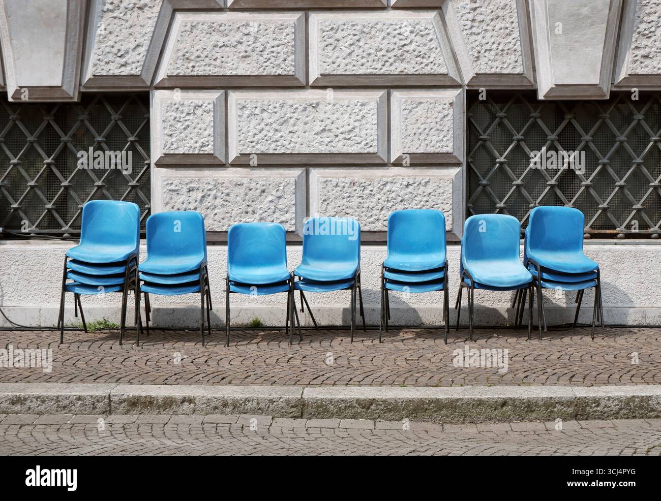 chaises bleues vides sur le trottoir contre le mur d'un bâtiment après un événement Banque D'Images