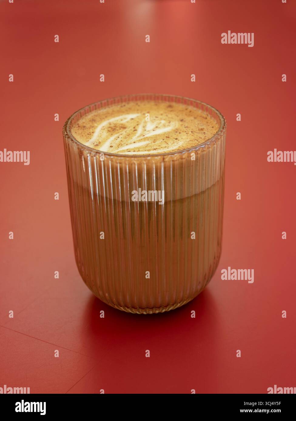 Latte cannelle dans un verre sur une table rouge Banque D'Images
