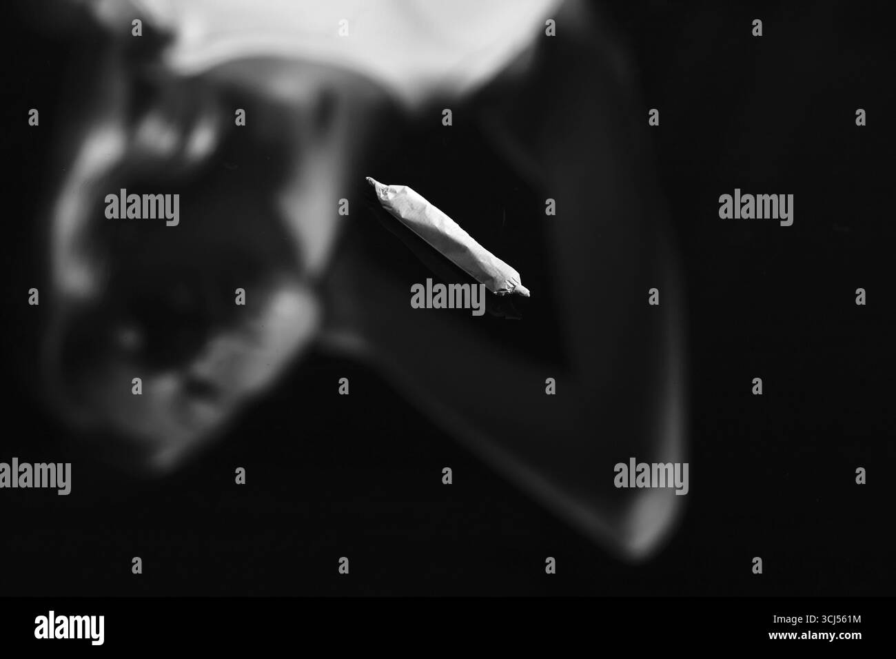 Joint avec de la marijuana sur fond de miroir noir avec réflexion floue féminine, monochrome Banque D'Images