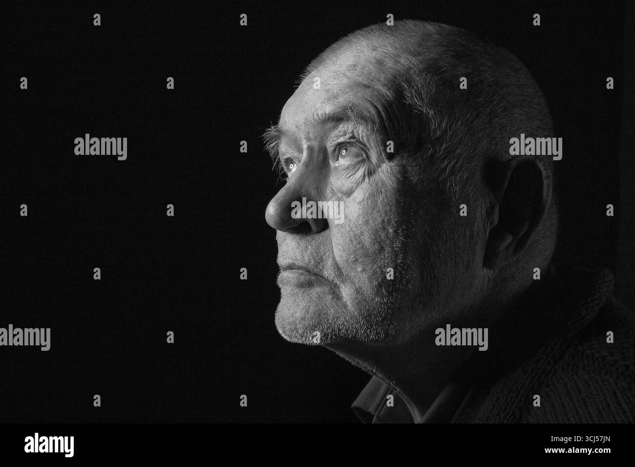 Vieil homme âgé regardant vers le haut dans une image monochrome sombre Banque D'Images