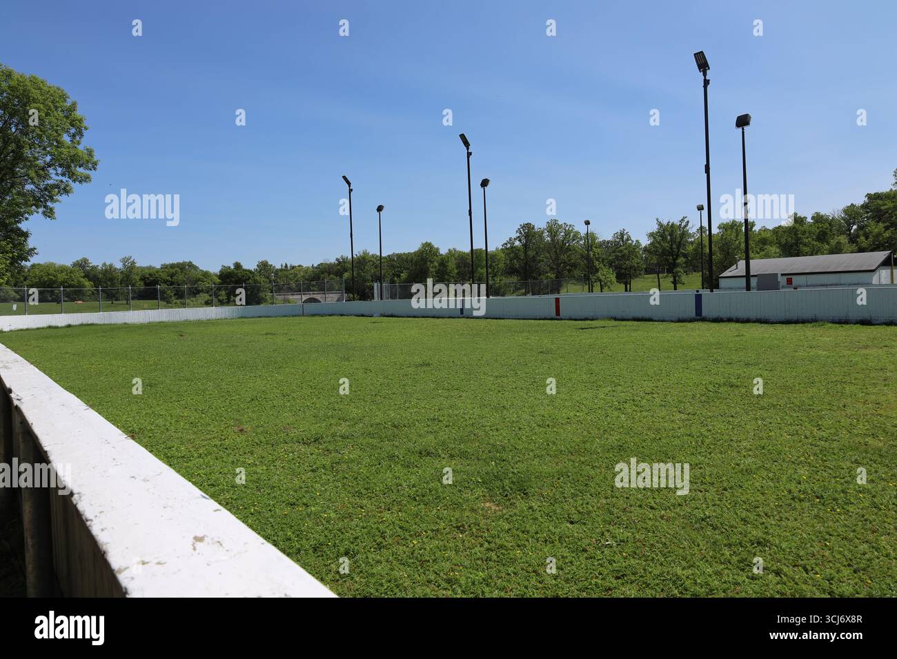 patinoire extérieure de hockey sur glace remplie d'herbe verte riche sous un ciel bleu clair lors d'une journée d'été ensoleillée Banque D'Images