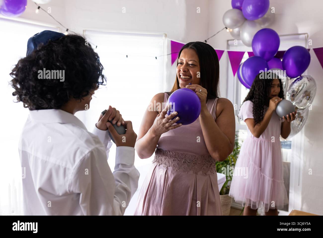 Célébrant l'événement religieux, la famille gonflant des ballons colorés ensemble à la maison joyeusement Banque D'Images