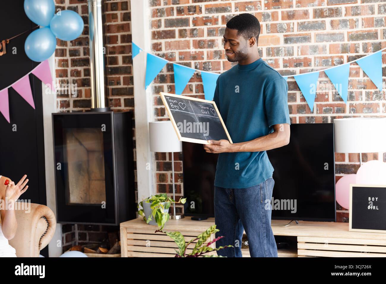 Homme tenant un tableau noir à la fête de révélation de genre, souriant et célébrant à l'intérieur Banque D'Images