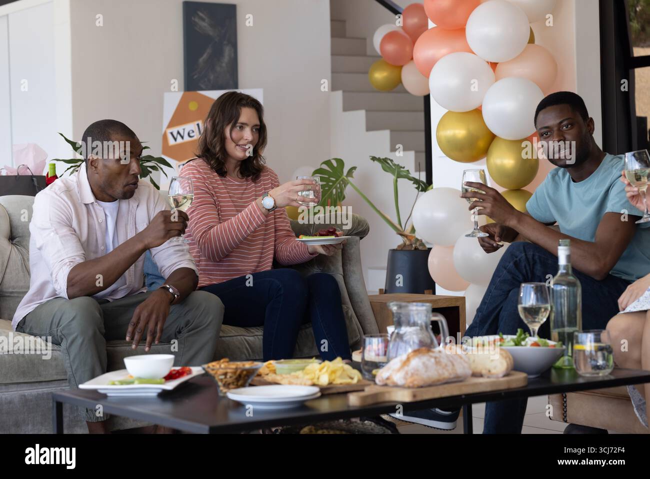 Amis célébrant à la maison avec des boissons et des collations, profitant d'une atmosphère festive Banque D'Images