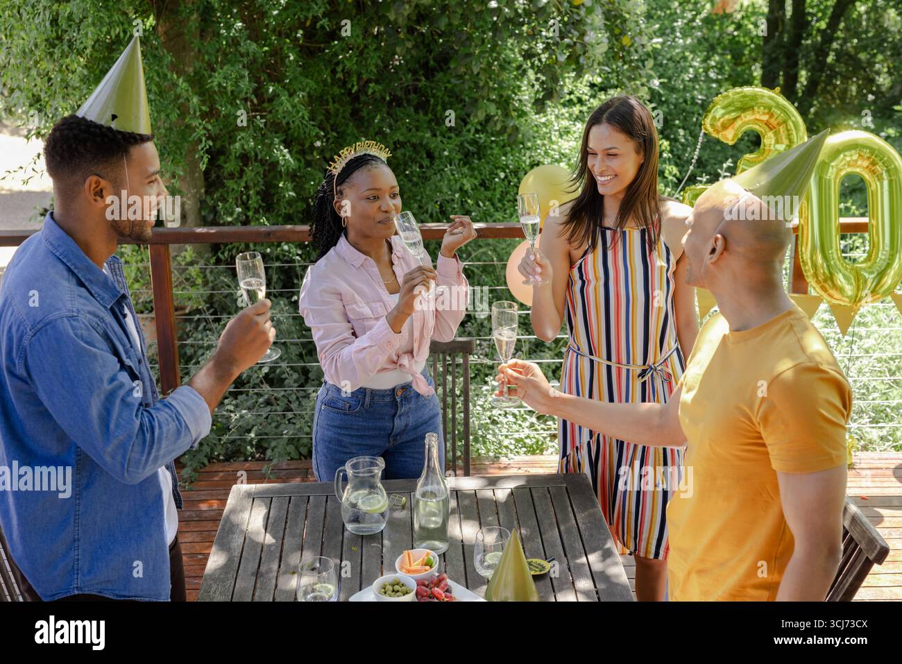 Célébration en plein air, amis avec champagne et chapeaux de fête lors d'une réunion festive Banque D'Images