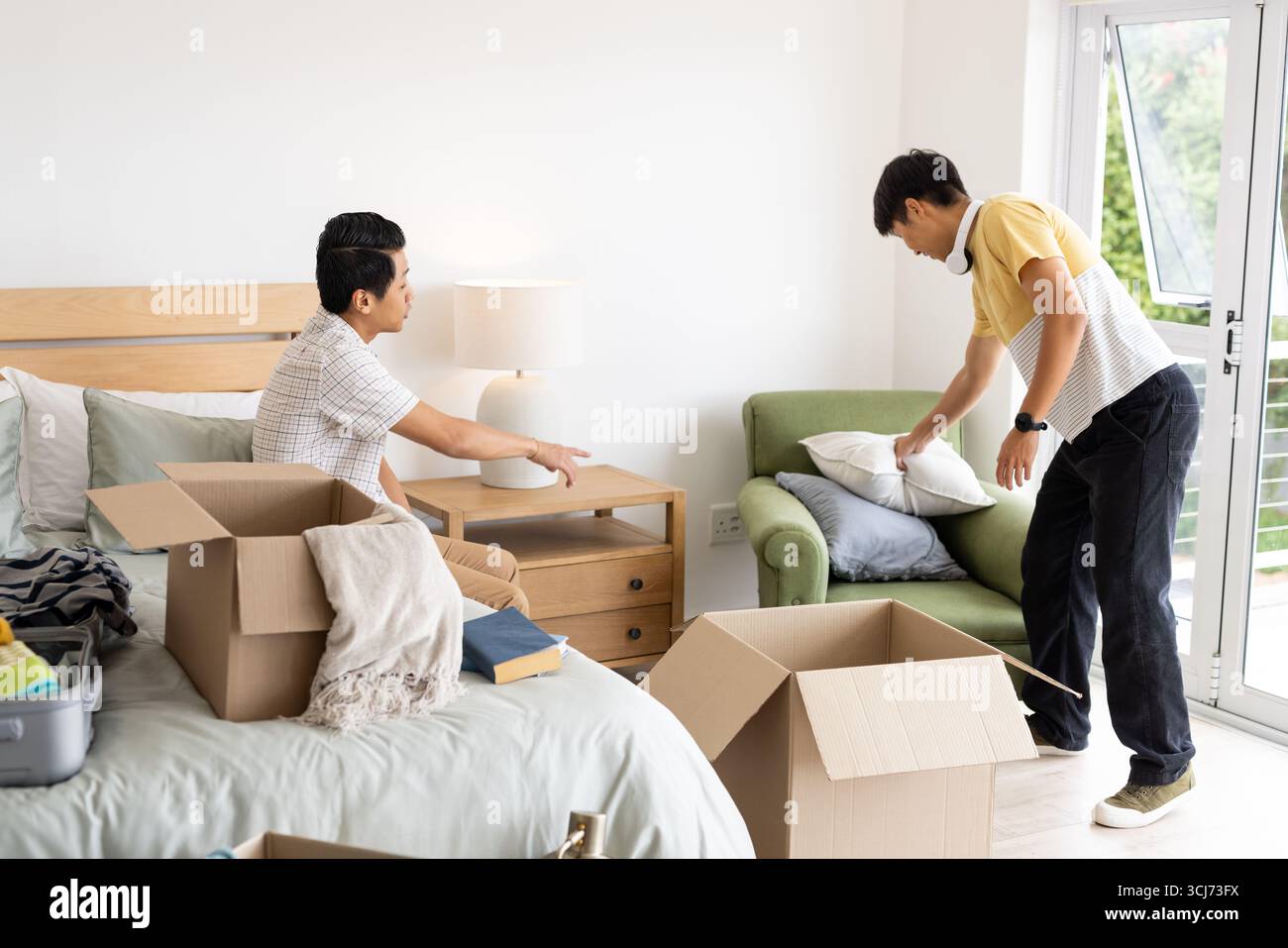 Amis déballant les boîtes et organisant la chambre, créant un espace de vie confortable ensemble Banque D'Images