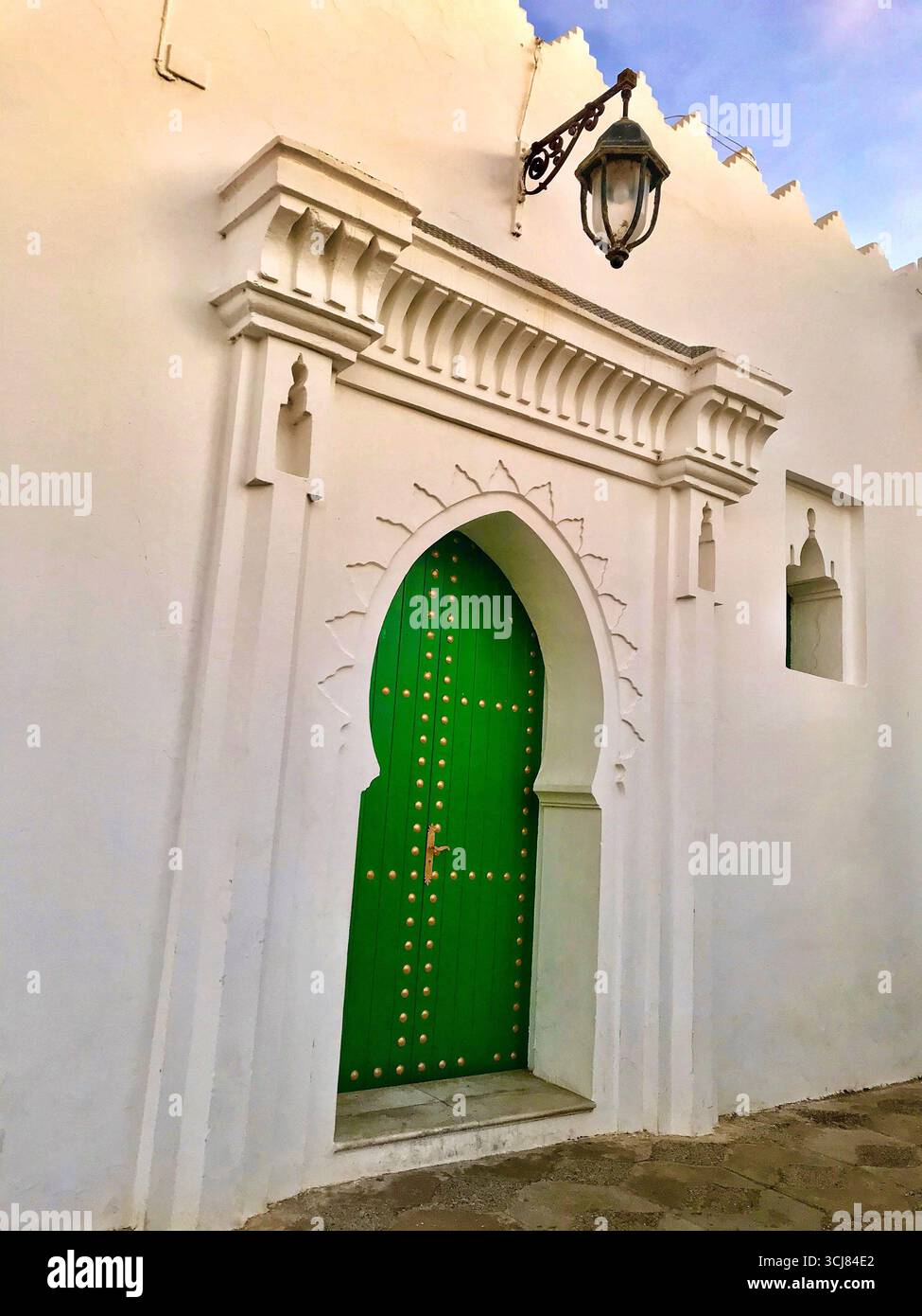 Porte mauresque traditionnelle dans la vieille médina de Tanger, au Maroc, avec stuc orné et porte verte avec des clous dorés. Prise le 10 octobre 2023. Banque D'Images