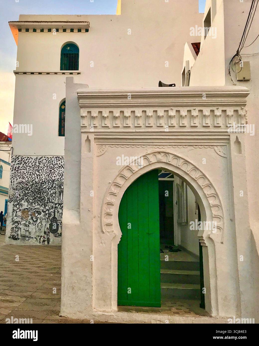 Porte mauresque traditionnelle dans la vieille médina de Tanger, au Maroc, avec stuc orné et porte verte avec des clous dorés. Prise le 10 octobre 2023. Banque D'Images