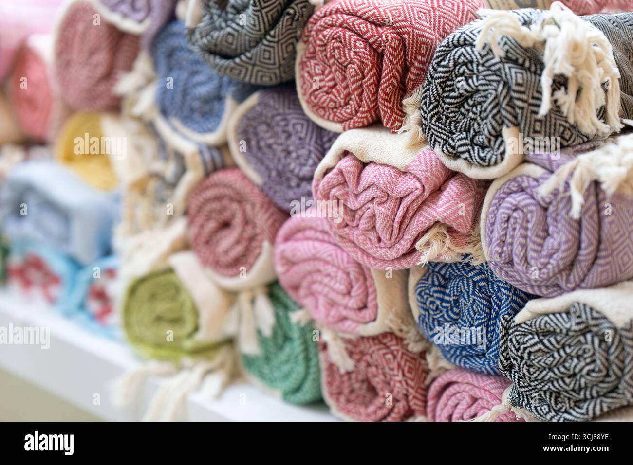 Vue rapprochée d'une pile de serviettes colorées à motifs, enroulées soigneusement et exposées dans un magasin. Photo de haute qualité Banque D'Images
