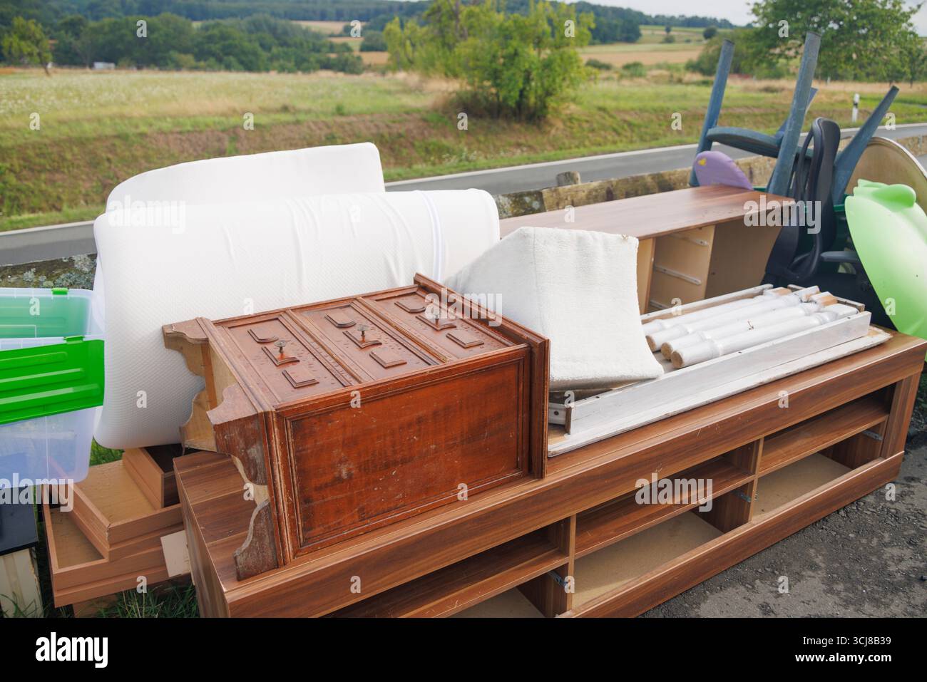 Meubles et articles ménagers jetés polluant un beau paysage naturel, soulignant le problème du déversement illégal Banque D'Images