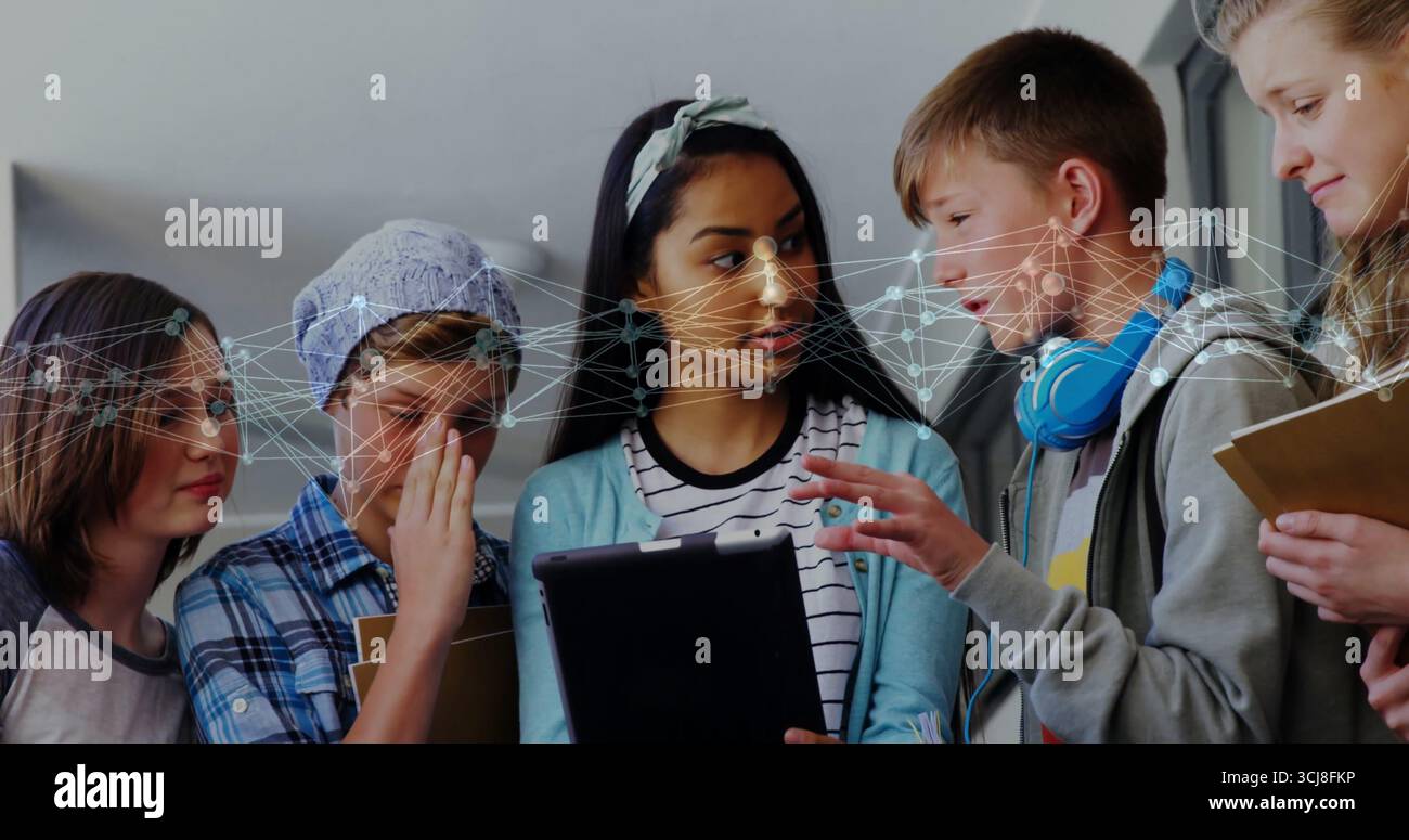 Collaboration de cinq élèves rassemblés autour de tablettes dans le couloir de l'école, avec reconnaissance faciale Banque D'Images