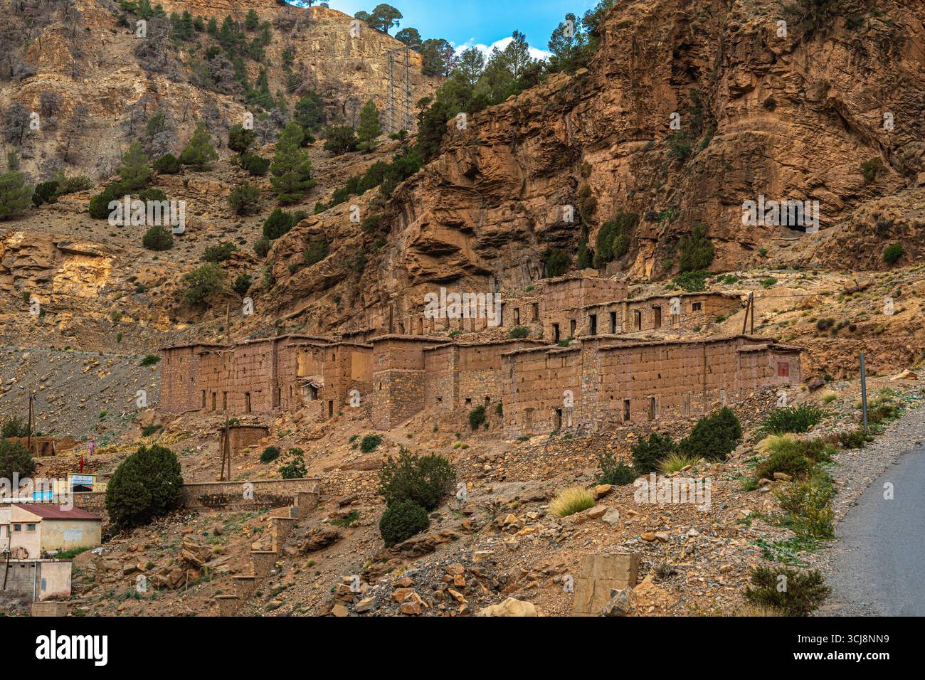 Maisons en Adobe dans un village marocain des montagnes de l'Atlas et des pentes boisées créant un paysage traditionnel pittoresque Banque D'Images