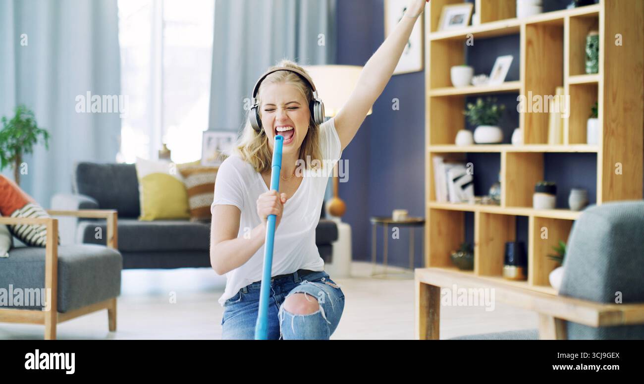 Femme, balai et chant avec nettoyage à la maison, écouteurs et heureux avec streaming dans le salon. Fille, excité et écouter de la musique avec audio Banque D'Images