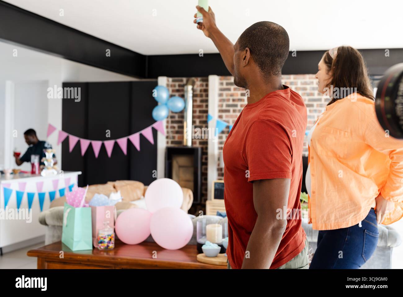 Amis célébrant à la maison avec des décorations, capturant des souvenirs sur smartphone Banque D'Images