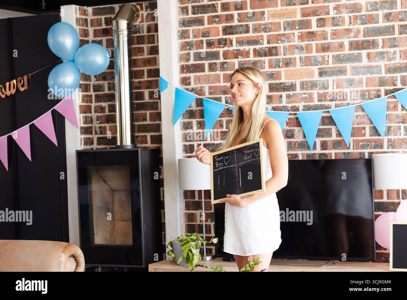 Femme tenant un tableau à la fête de révélation de genre, souriant avec des décorations festives Banque D'Images