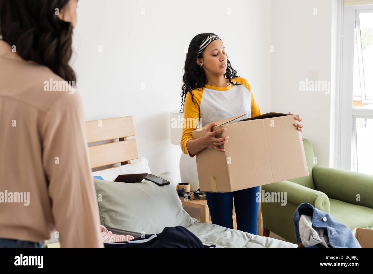Femme portant la boîte en carton dans la chambre tout en organisant et rangeant l'espace Banque D'Images