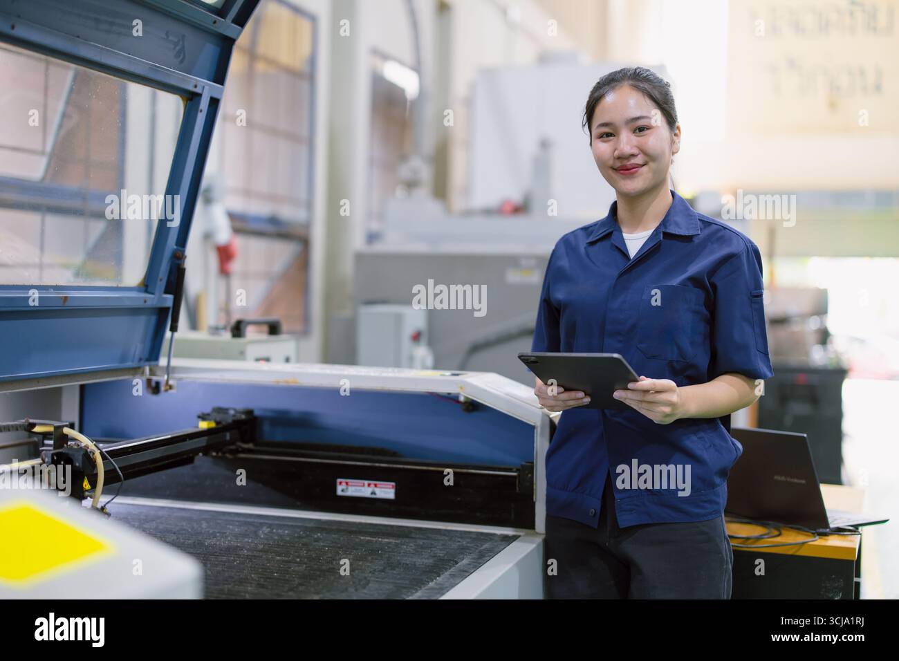 Heureux jeune technicien technicien ouvrier commande faire fonctionner la machine de découpe laser en métal dans l'usine moderne de l'industrie lourde en acier Banque D'Images