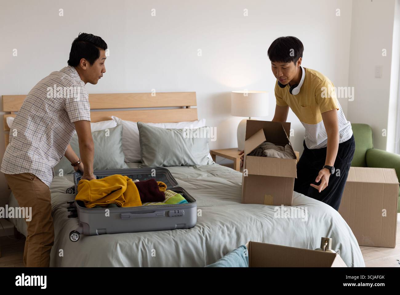 Emballage valise et boîtes, deux hommes organisant les affaires dans la chambre Banque D'Images