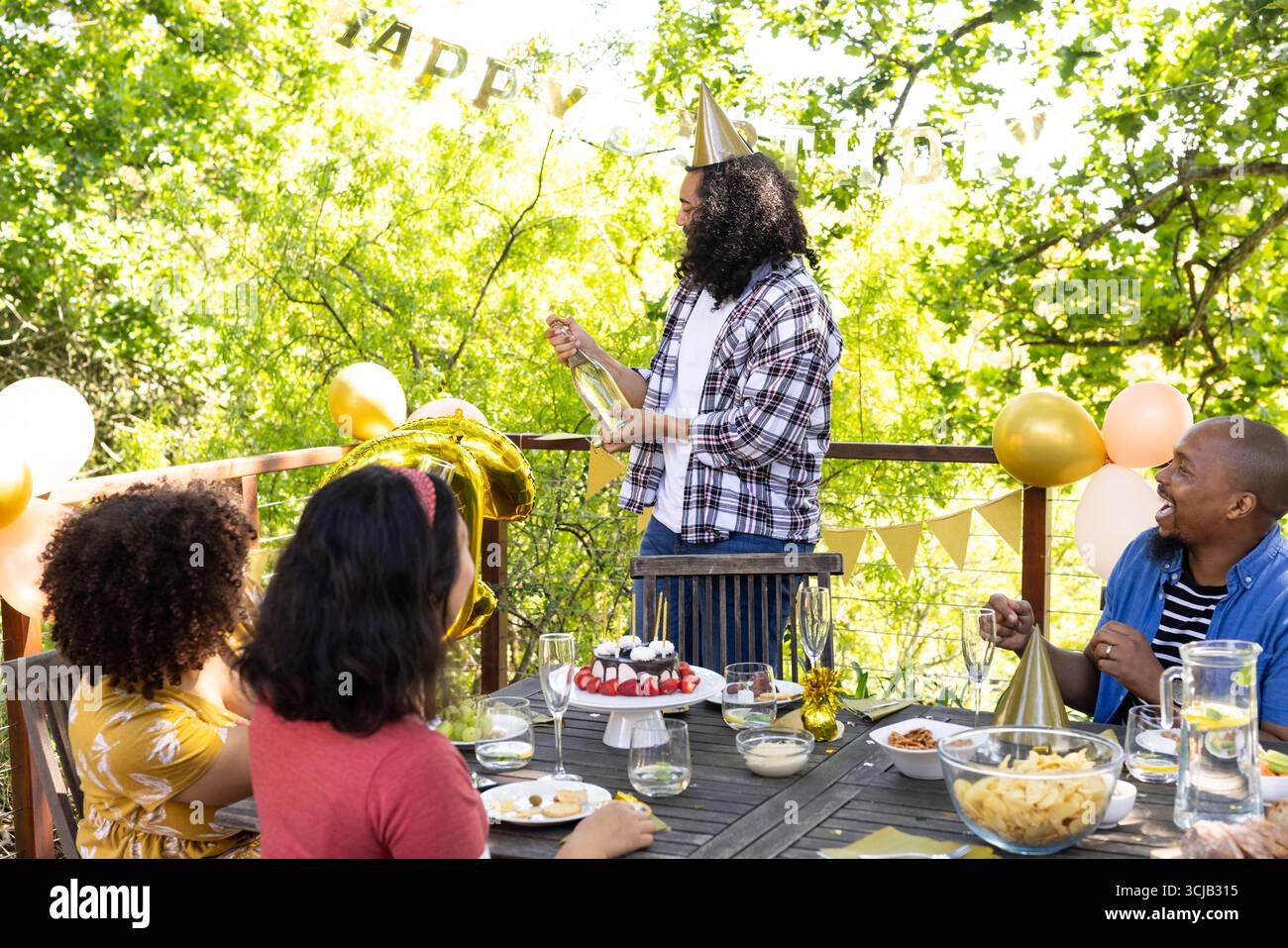 Fête d'anniversaire en plein air, amis divers avec gâteau et champagne ensemble Banque D'Images