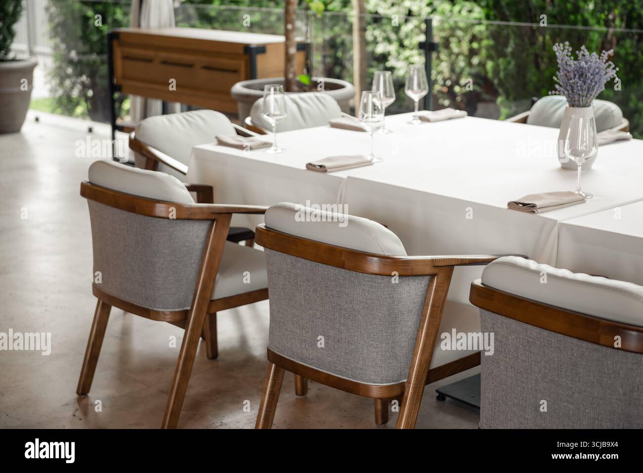 Table et chaises vides dans un restaurant. Terrasse extérieure avec chaises en bois gris et table recouverte de tissu blanc. Banque D'Images