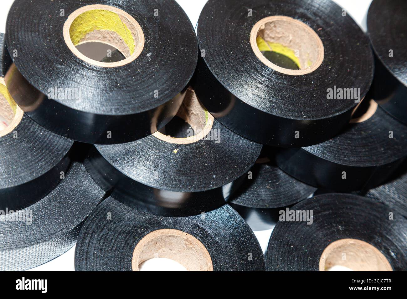 Plusieurs écheveaux de ruban électrique noir empilés les uns à côté des autres, gros plan. Banque D'Images